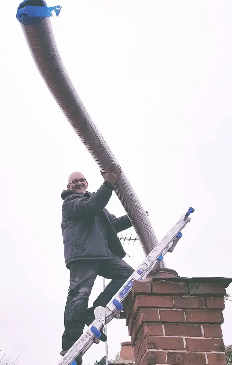 Tony Preston installing a flue liner in a chimney after a stove installation in Wirral